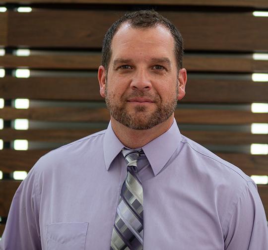 headshot of man with shirt and tie, beard