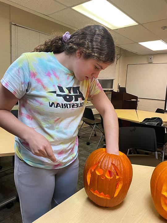 young woman carving a pumpkin