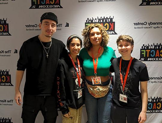 four people, students, standing in front of banner