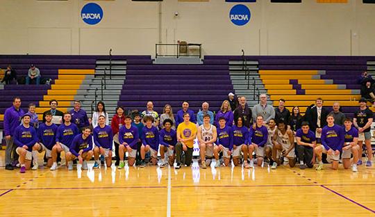 group of men's basketball players pictured with a row of faculty and staff