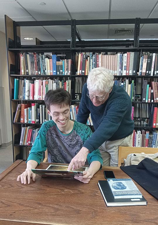 two people looking over a book in a library