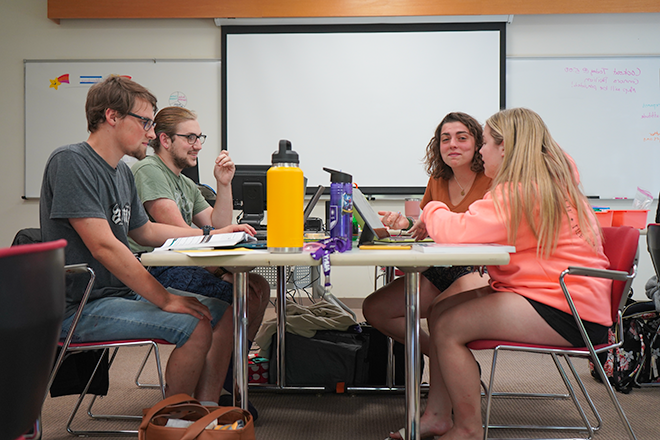 4 students at a desk in class